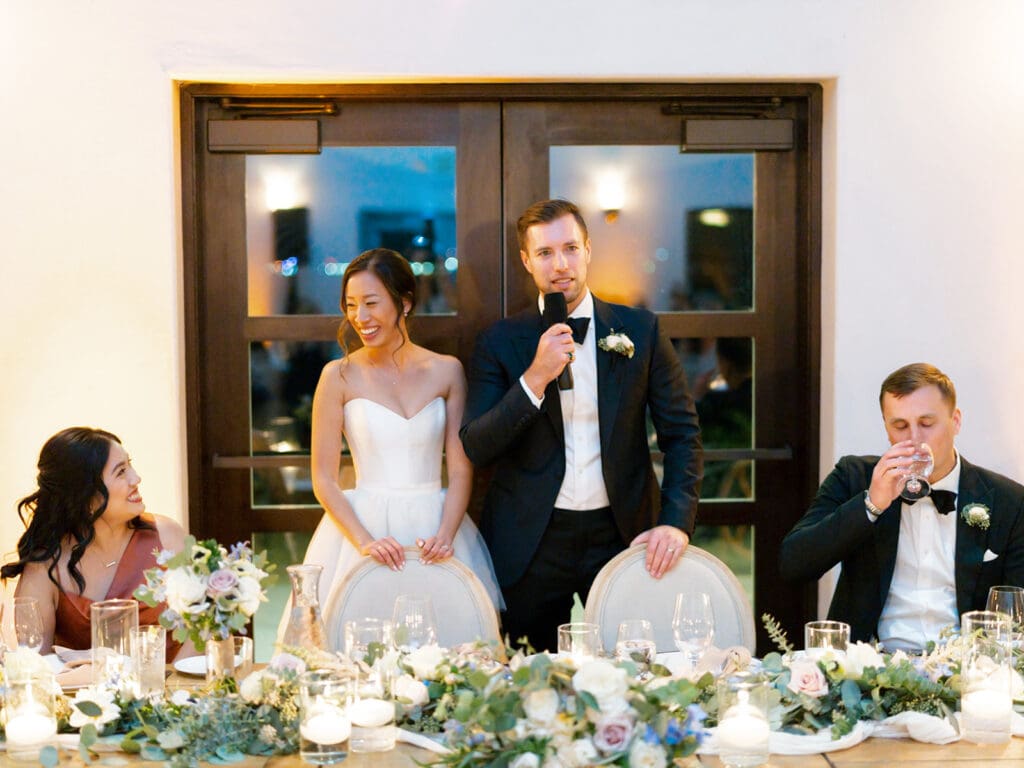 Bride and groom standing while they give a speech during their reception