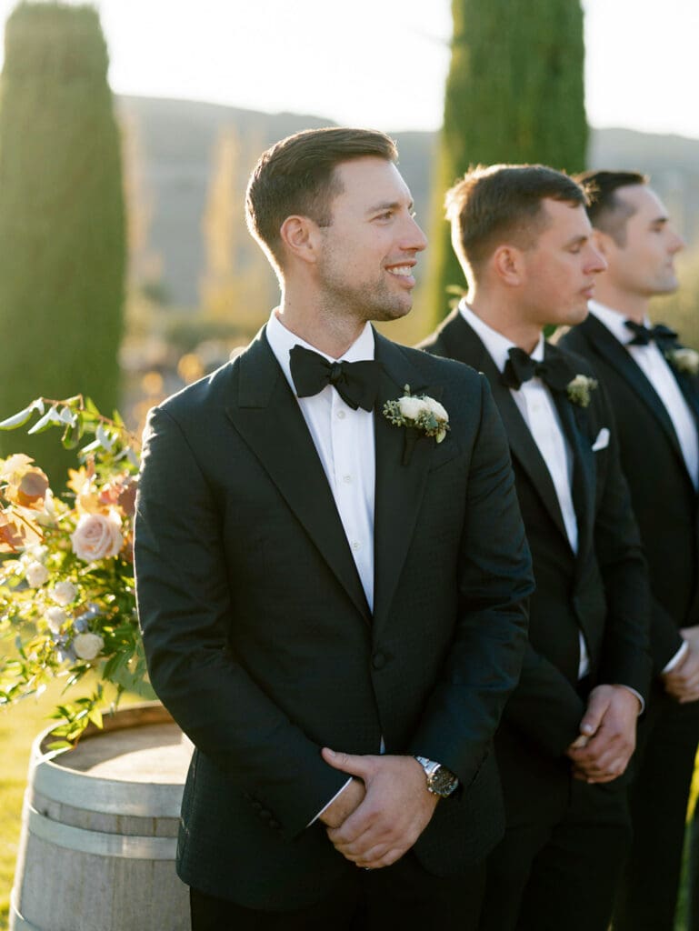 Groom smiling as he sees his bride walking down the aisle with her father