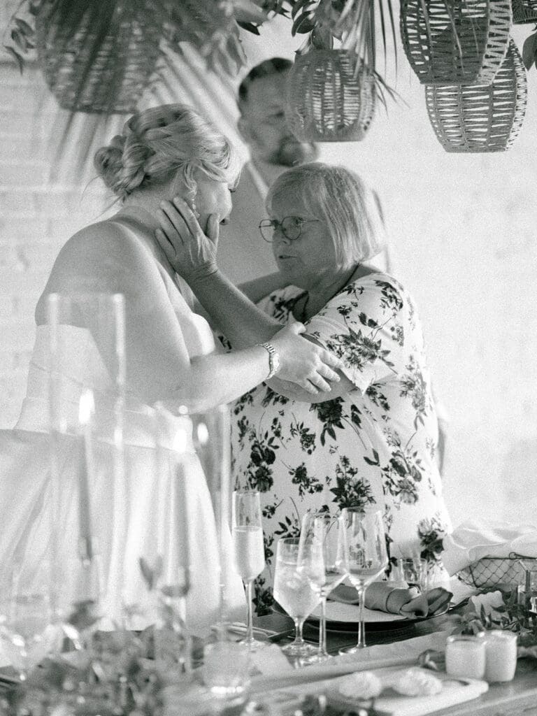 Black and white photo of a bride hugging a guest during speeches