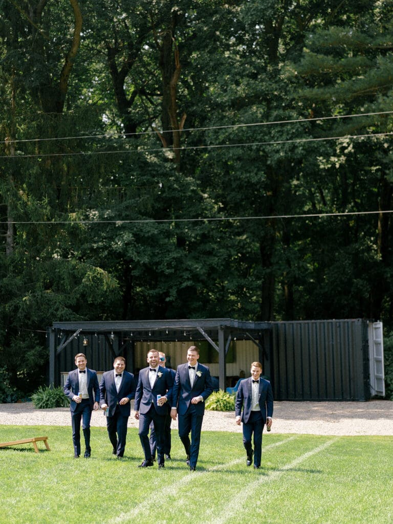 Groom and his groomsmen walking in front of the Hop House at Greencrest Manor - Estate wedding venue in Michigan