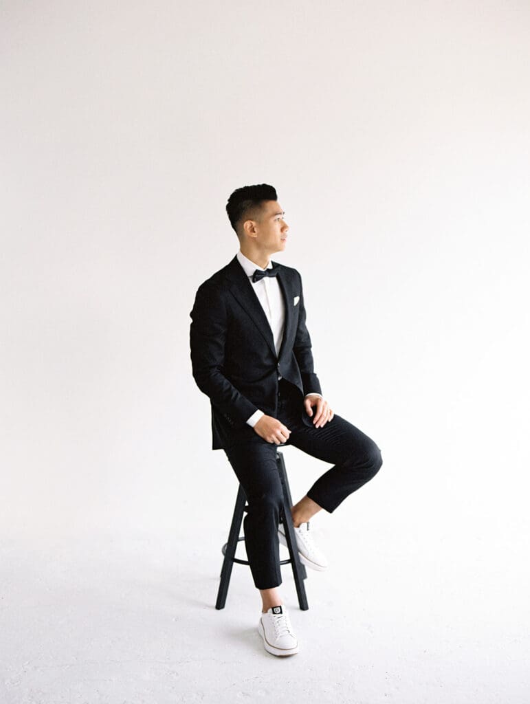 Grooms sitting on a stool for his in studio portraits in South Bend, Indiana