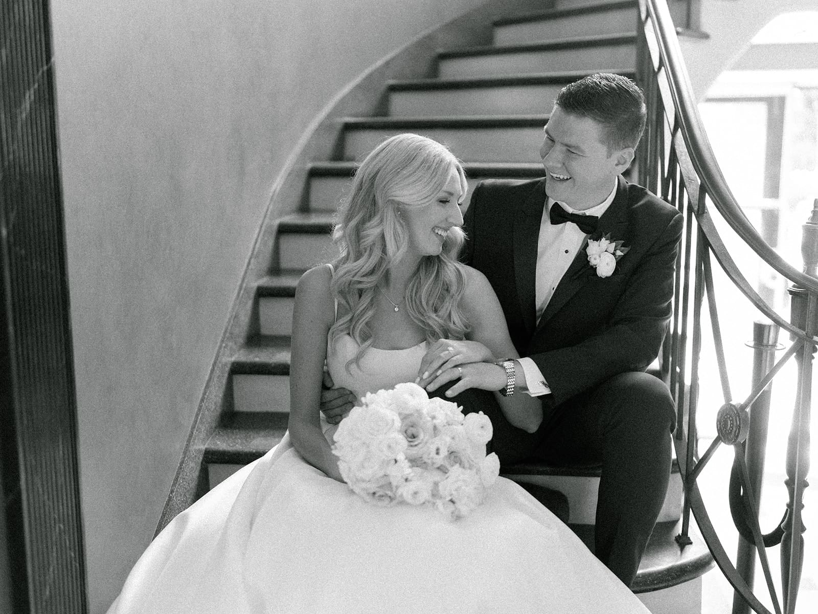 Black and white photo of a bride and groom sitting on the staircase at Greencrest Manor - Estate wedding venue in Michigan