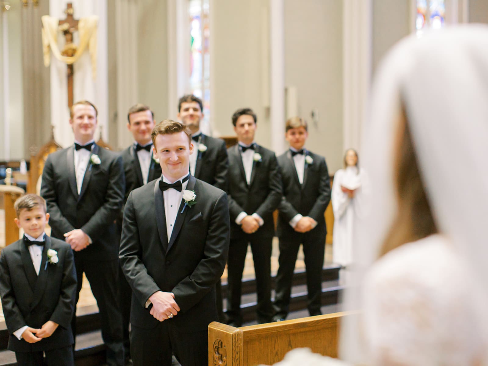 Groom smiling as he sees his bride walking down the aisle towards him during their Cathedral Basilica of The Sacred Heart Wedding ceremony at Notre Dame