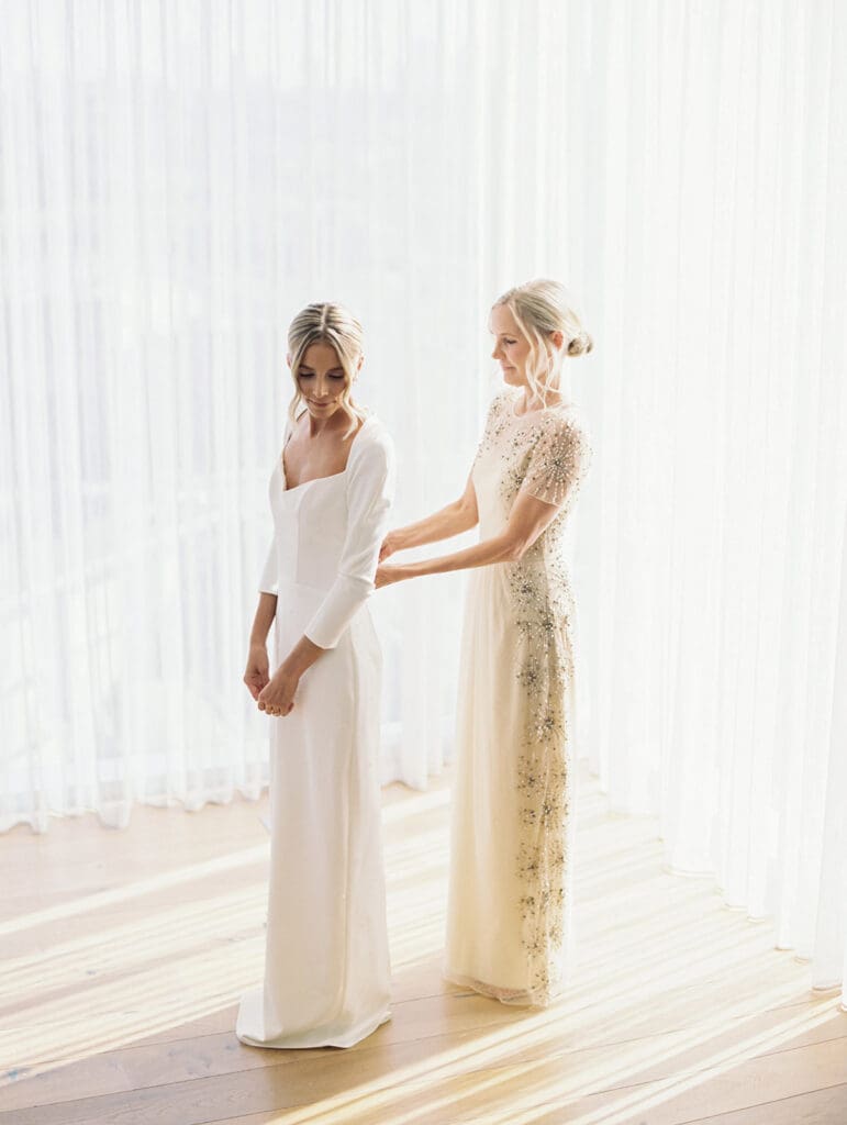 Brides mother zipping up her wedding dress