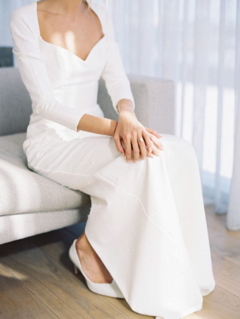Close up shot of a bride wearing her classic long sleeved wedding dress and white heels