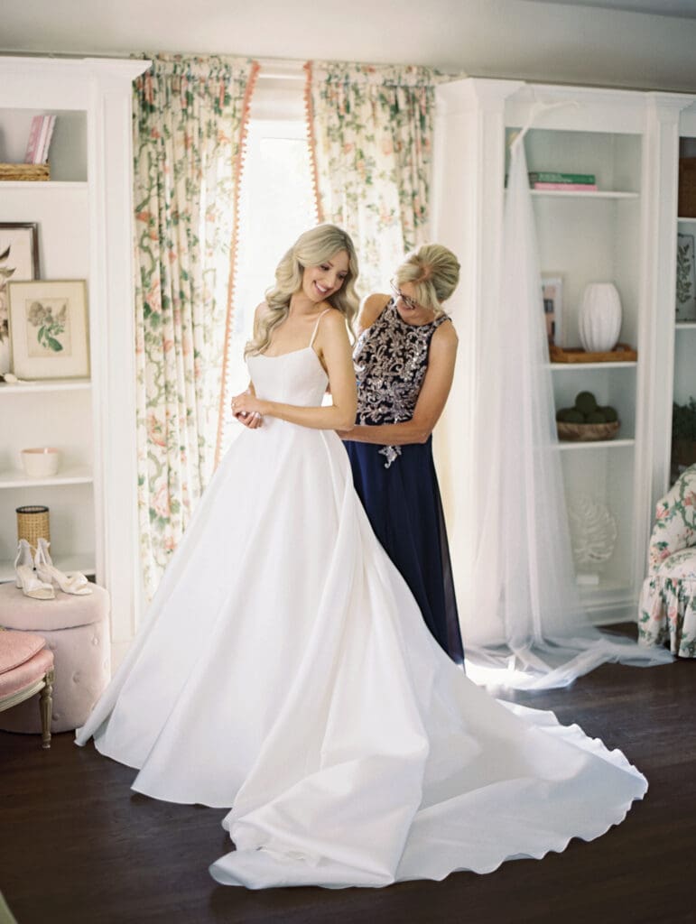 Bride getting her dress done up by her mother