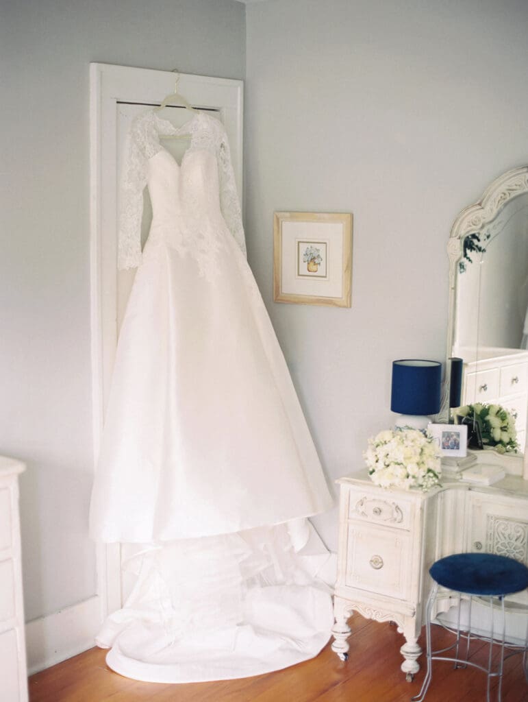 Traditional long sleeved wedding dress hanging from a closet door