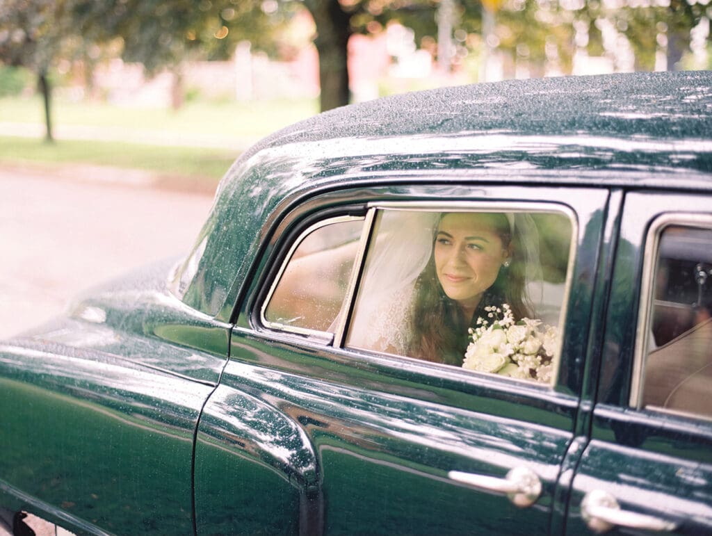 Bride riding in a vintage green car to her University of Notre Dame wedding