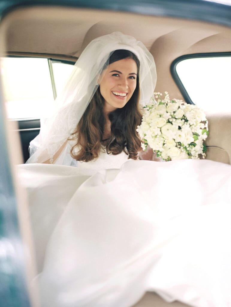 Bride smiling as she sits in a vintage green car
