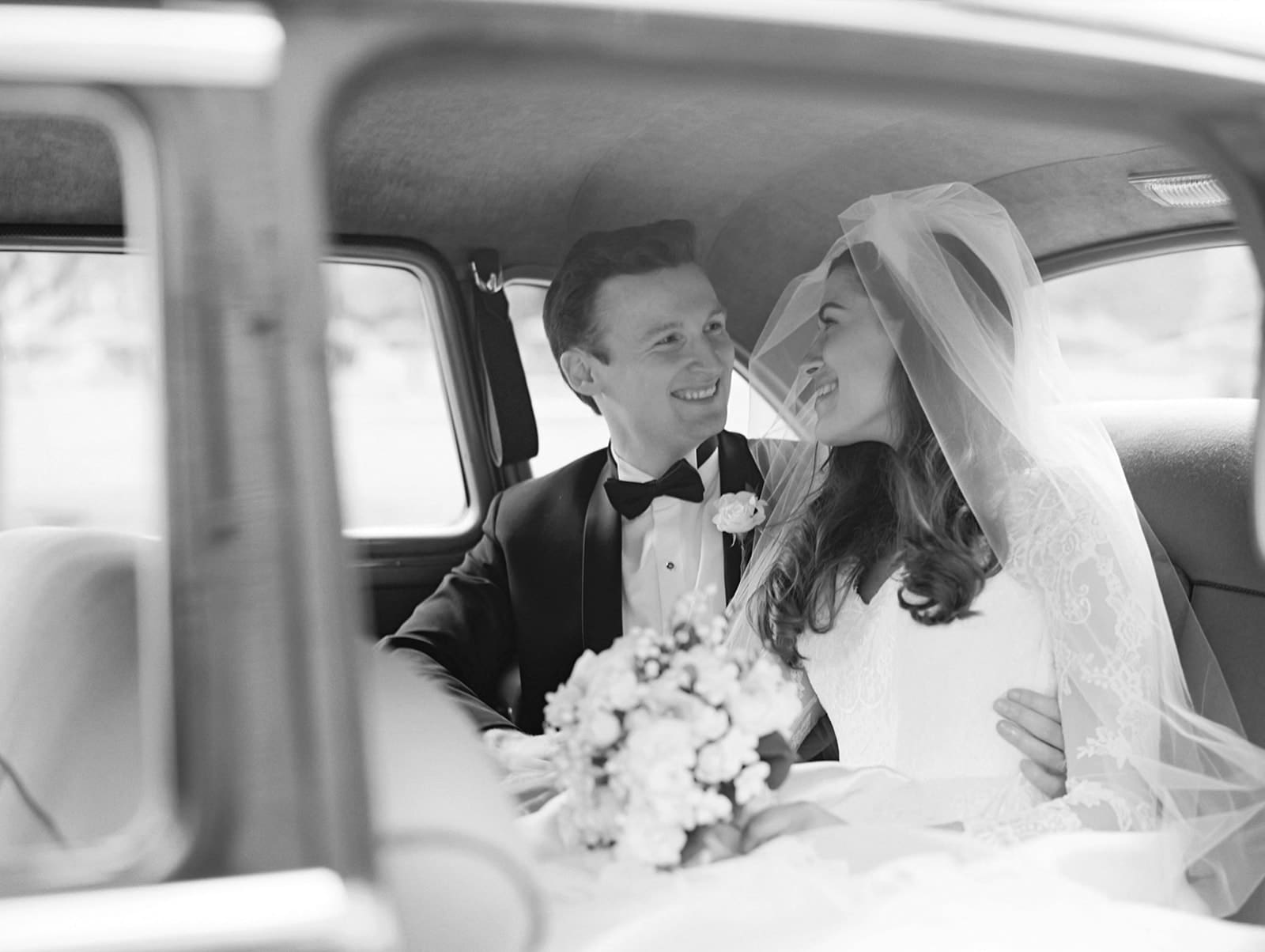 Black and white photo of a bride and groom in a vintage car