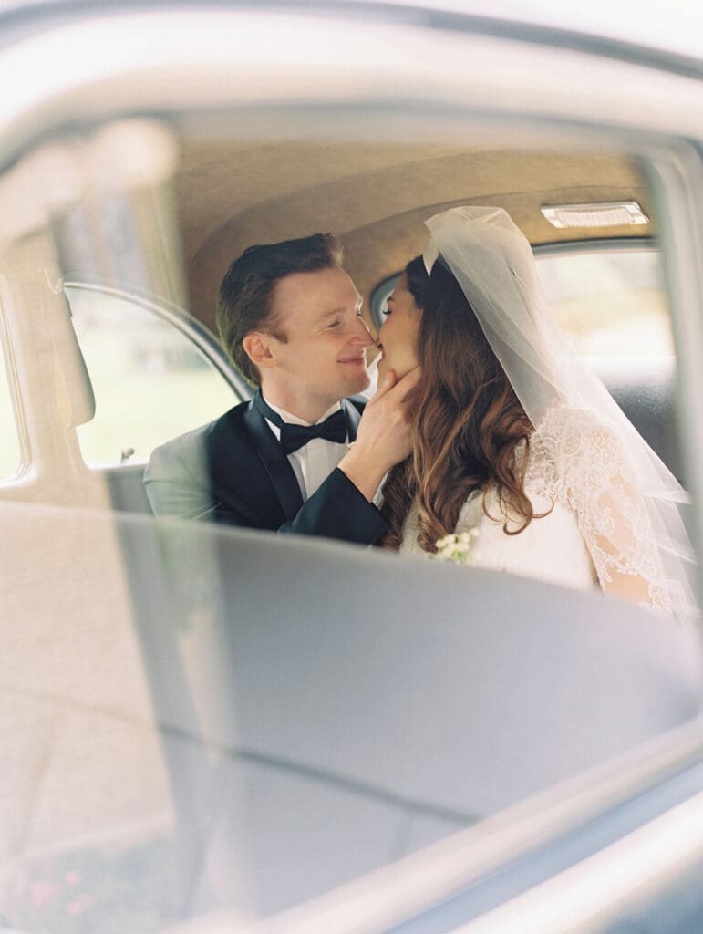 Bride and groom posing for portraits in a vintage car