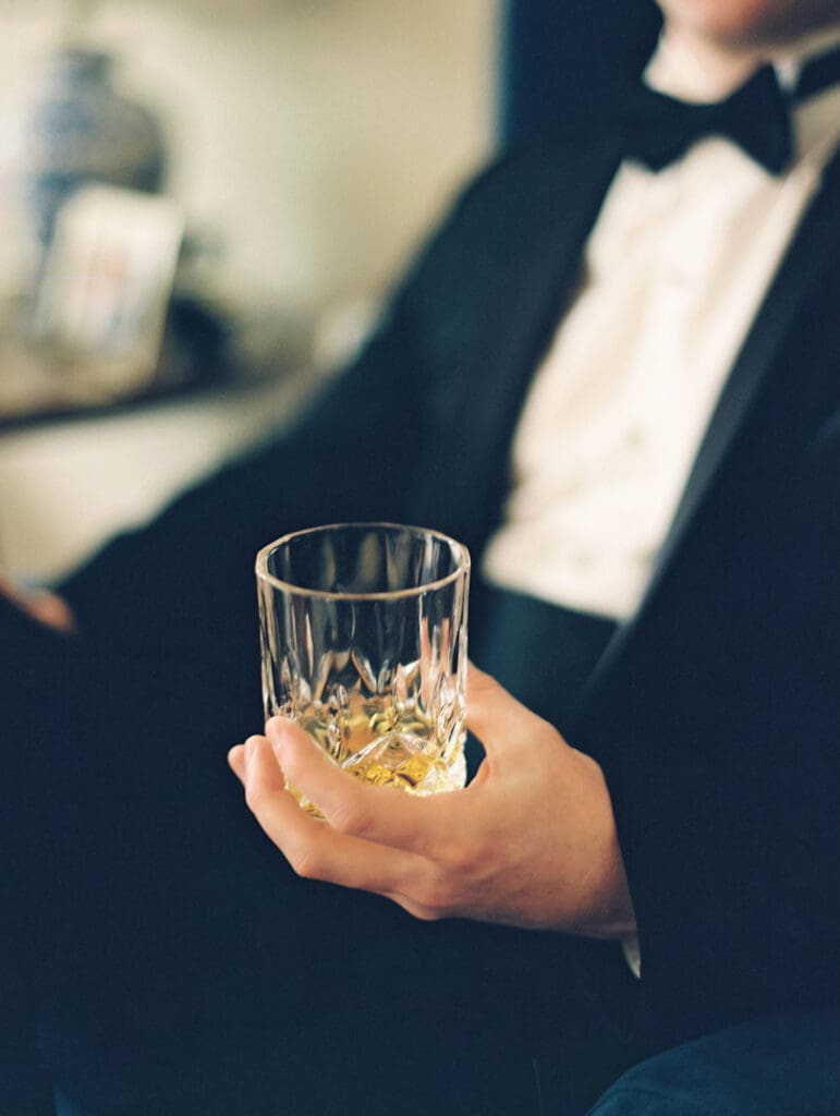 Close up detail shot of a groom holding a whiskey glass