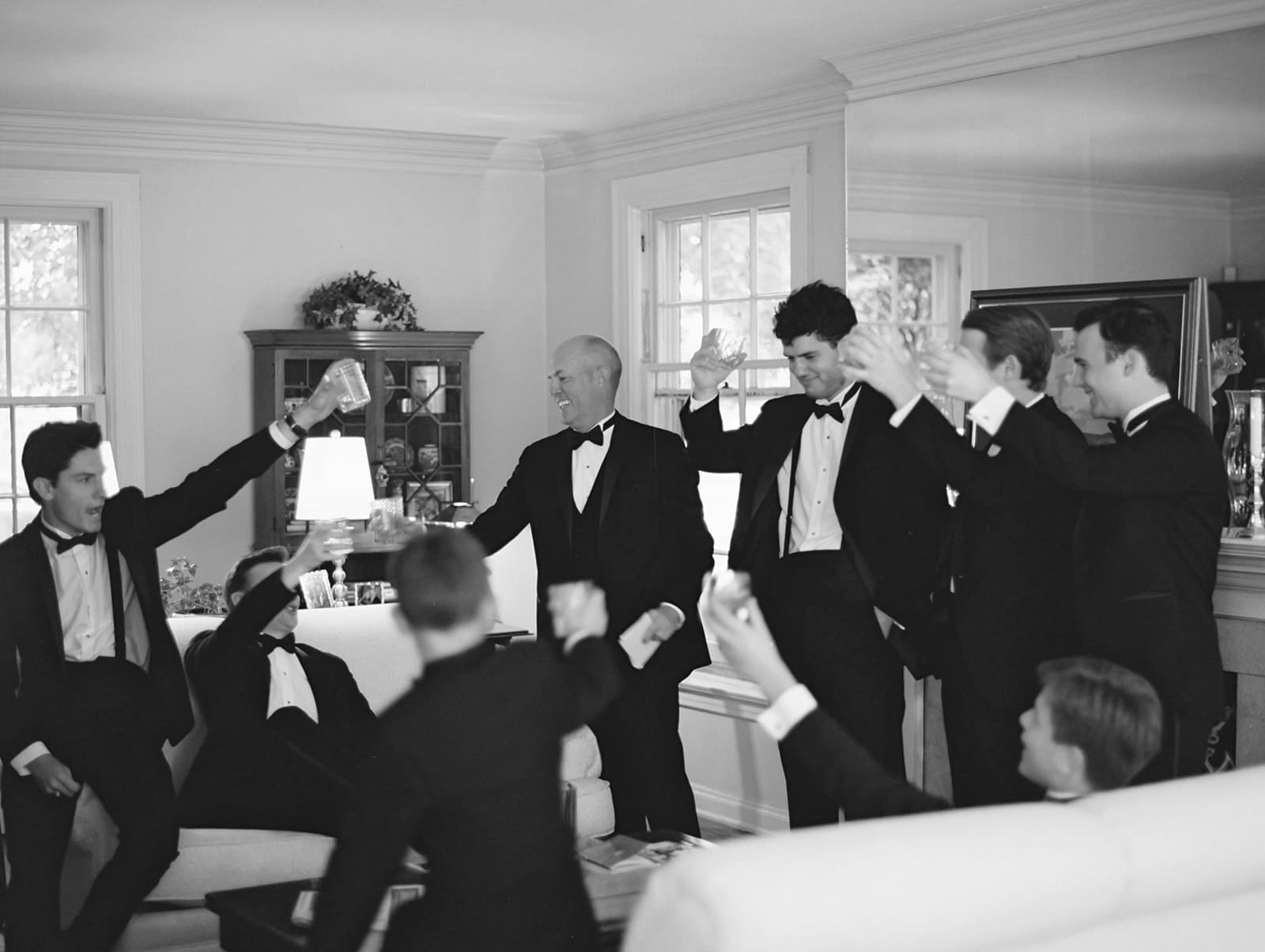 Black and white photo of the groom and groomsmen toasting heir drinks