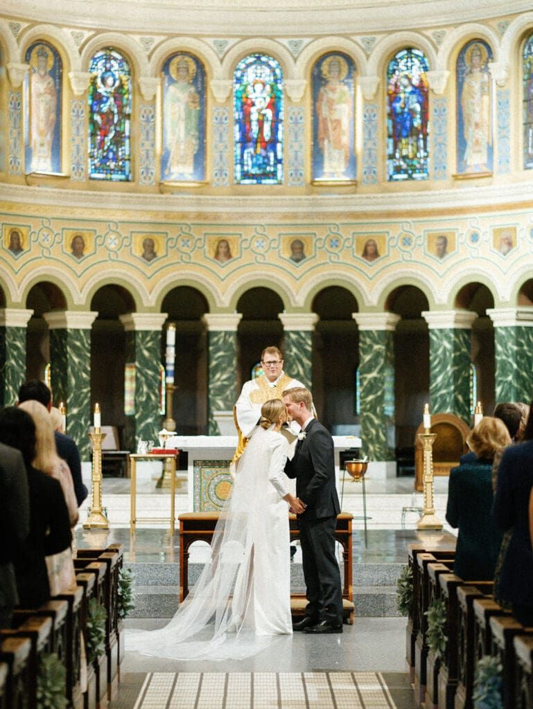 Bride and groom kissing during their downtown Chicago wedding ceremony at Saint Clement Parish