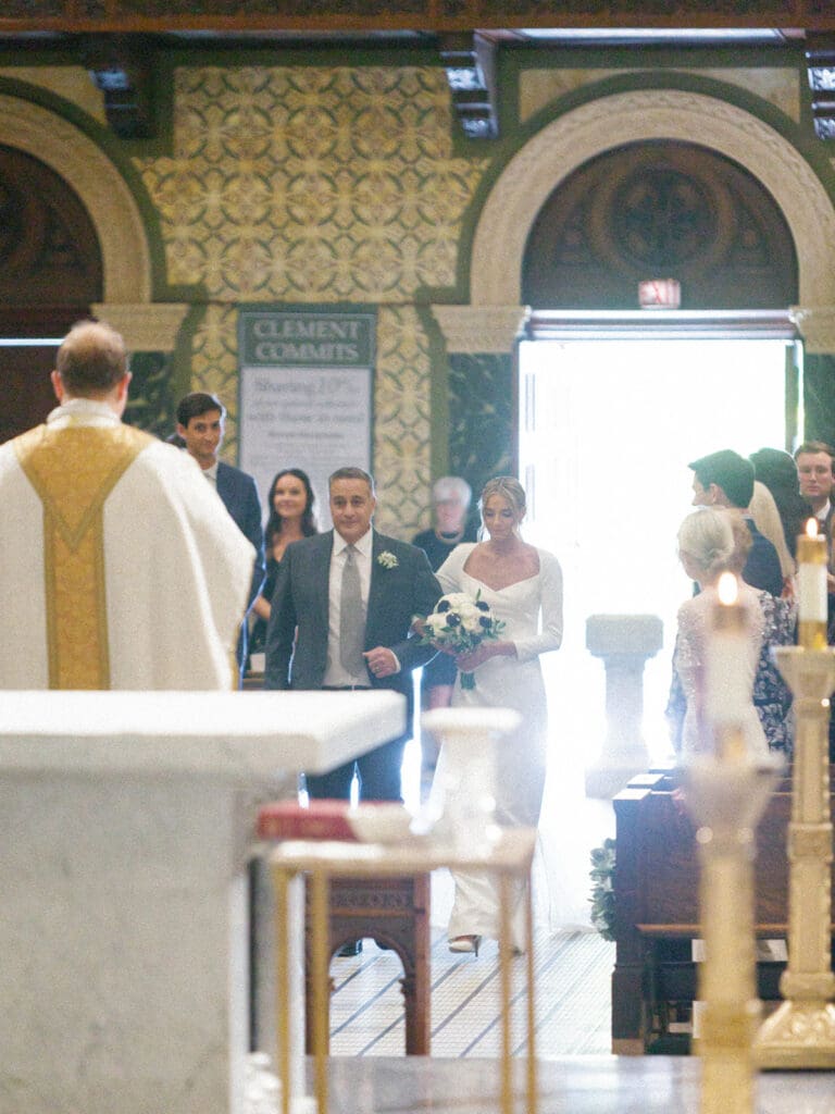 Bride being walked down the aisle by her father for her Saint Clement Parish wedding ceremony in Chicago, Illinois