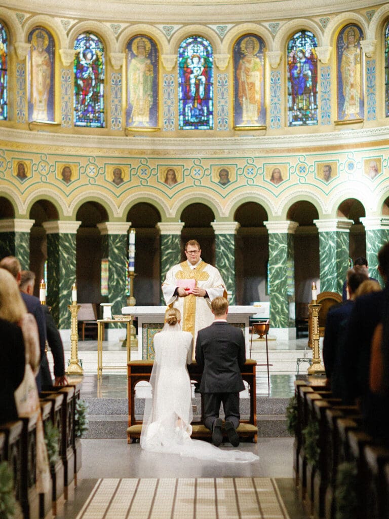 Bride and groom kneeling during their downtown Chicago wedding ceremony at Saint Clement Parish