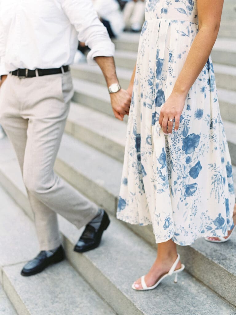 Close up photo of a couple holding hands and walking down stairs