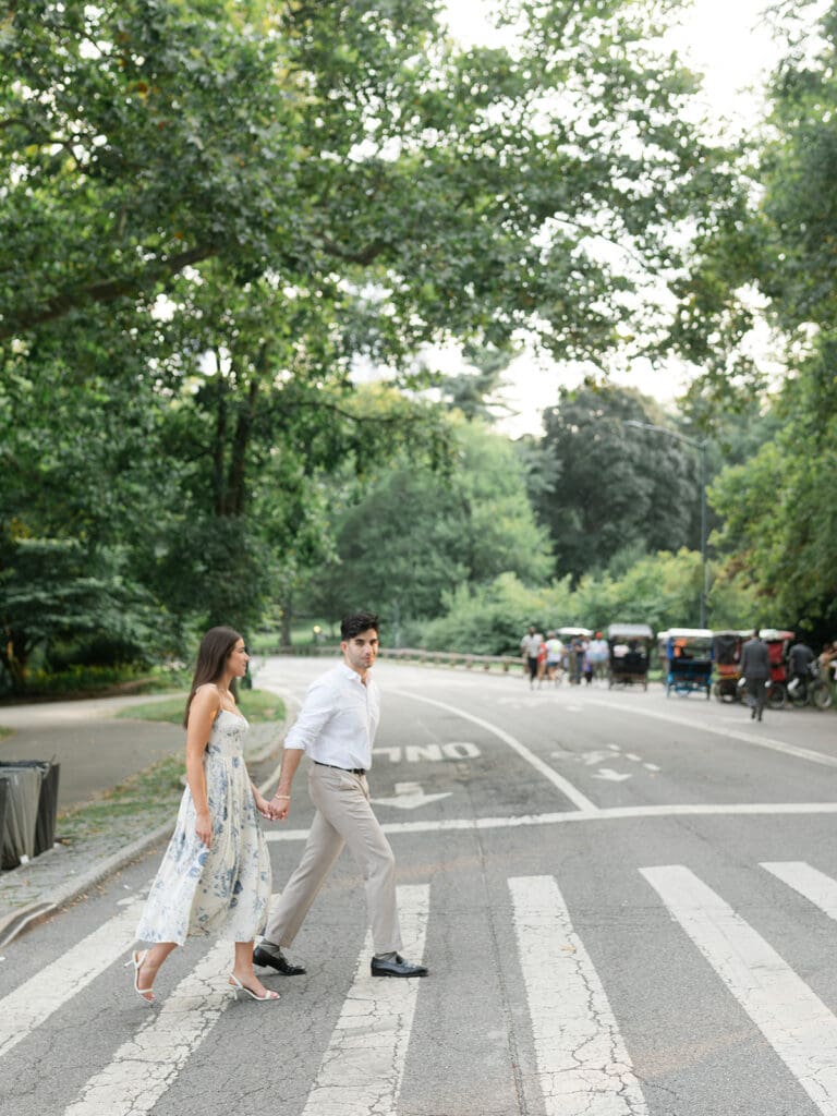 Couple holding hands and crossing the street during their New York City engagement shoot