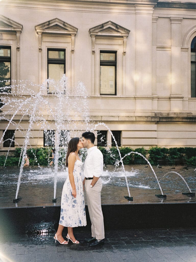 Couple kissing in front of a water fountain during their New York engagement shoot