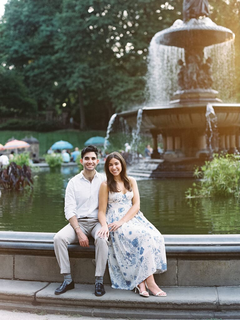 Couple sitting at Bethesda Fountain for their Central Park engagement photos in NYC