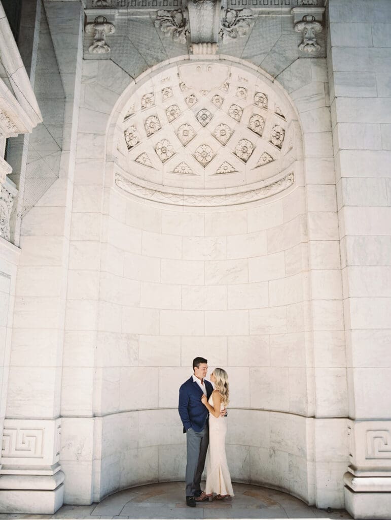 Man and woman posing for their New York Public Library engagement photos
