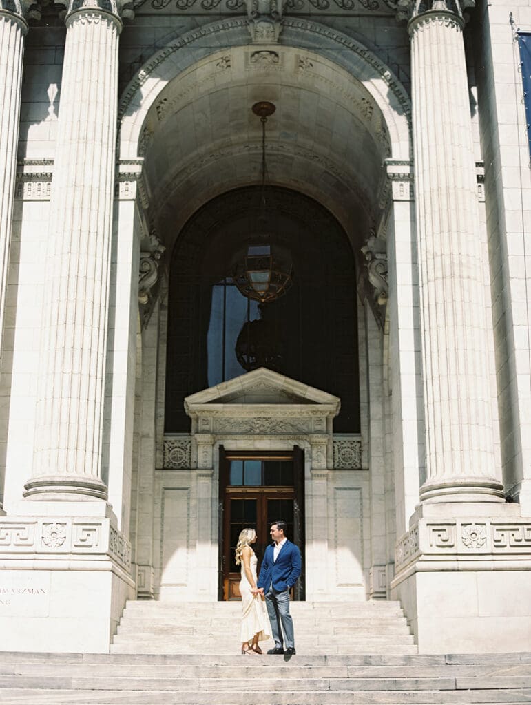 Couple posing in front of the building for their New York Public Library engagement photos