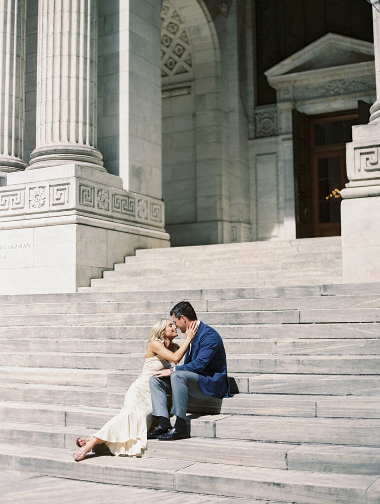 Couple sitting on the steps for their New York Public Library engagement photos
