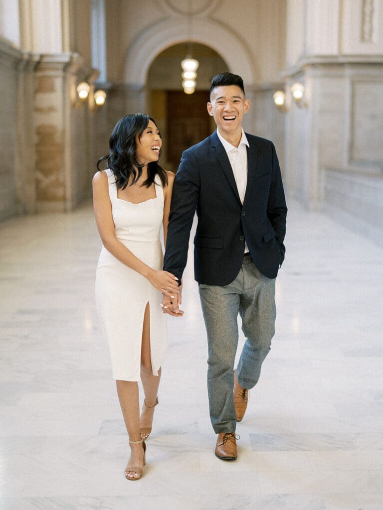 Couple laughing as they walking during their San Francisco City Hall engagement photos