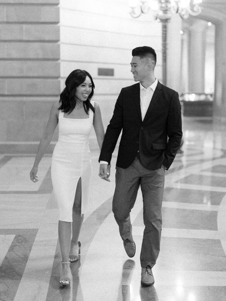 Black and white photo of a couple walking in the San Francisco City Hall