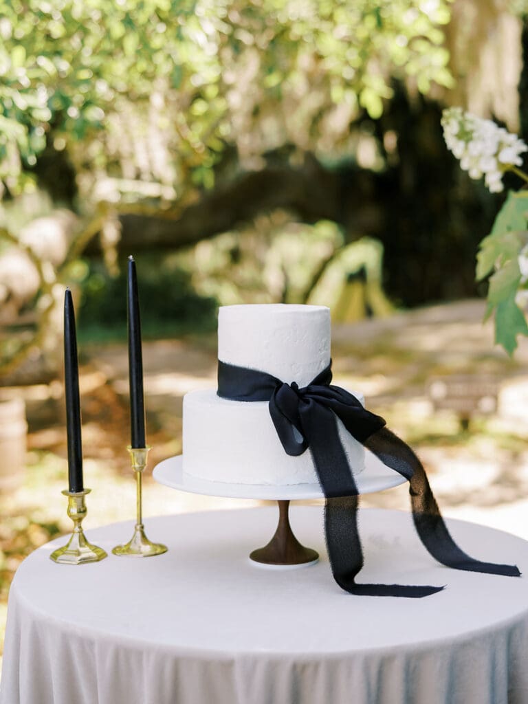Two-tiered white wedding cake with a black bow