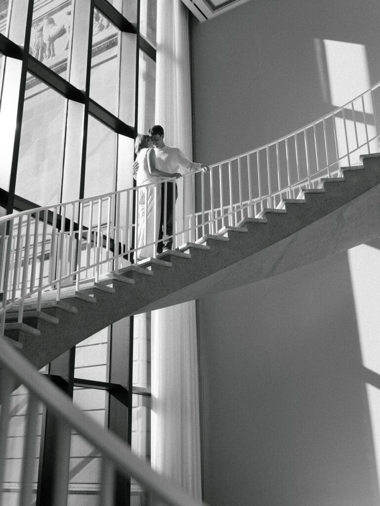 Couple embracing on a modern staircase inside the Art Institute of Chicago, a luxury Chicago wedding venue with iconic architecture