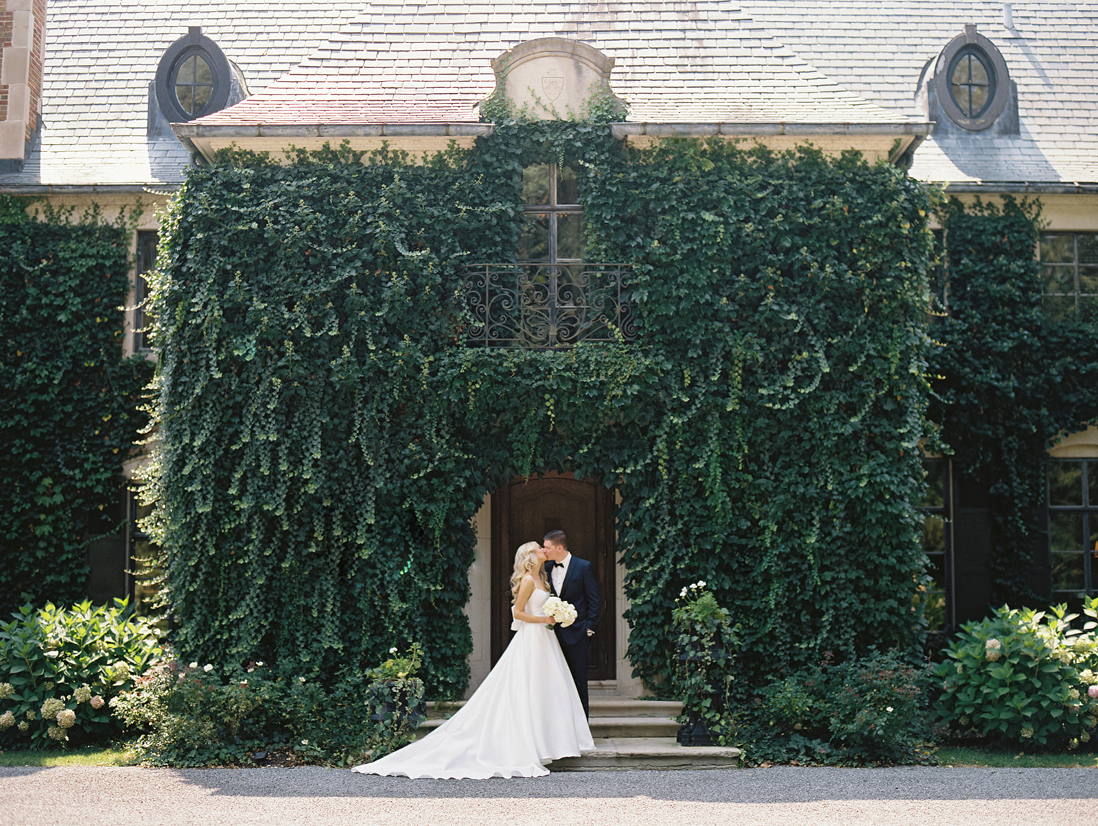 Bride and groom kissing in front of Greencrest Manor wedding venue in Battle Creek, Michigan